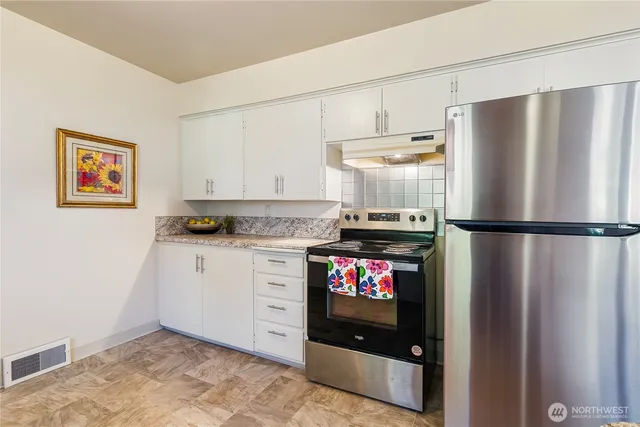 a kitchen with stainless steel appliances granite countertop a refrigerator and a stove