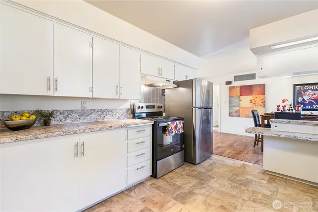 a kitchen with granite countertop a sink stainless steel appliances and white cabinets