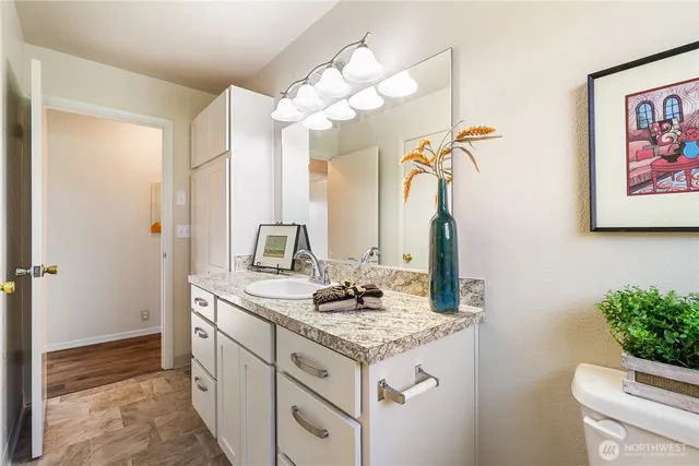 a bathroom with a granite countertop sink a toilet and a mirror