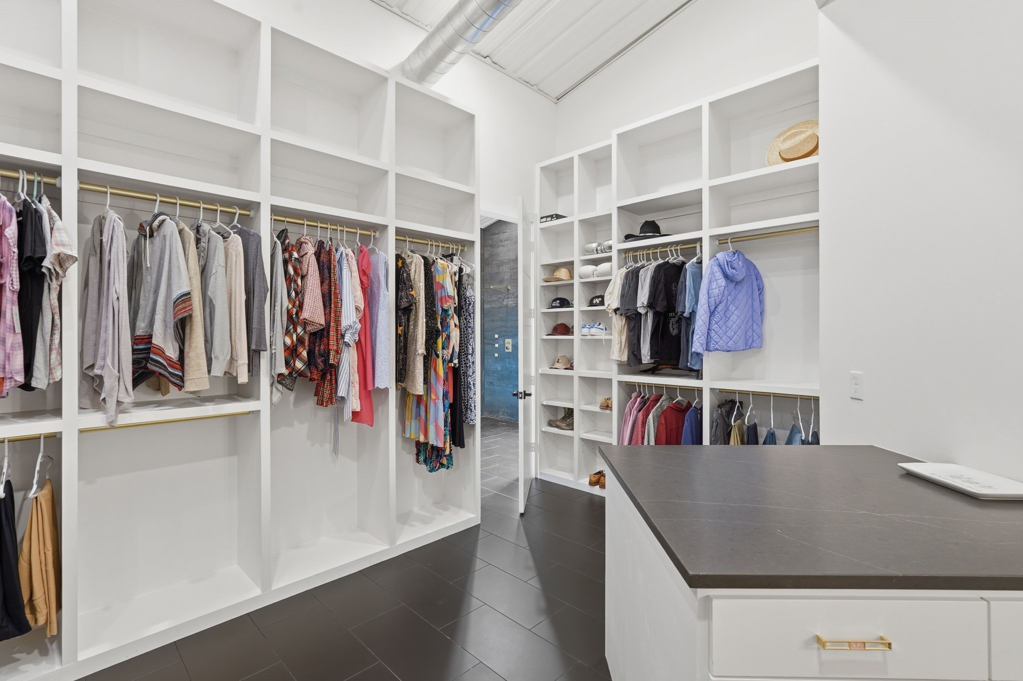 2743 Bobville Road Montgomery, TX 77316 - Photo 33 of 50 This photo showcases a spacious, organized walk-in closet with ample shelving and hanging space for clothes, hats, and accessories. It features a sleek island with drawers, modern decor, and a well-lit, open design.