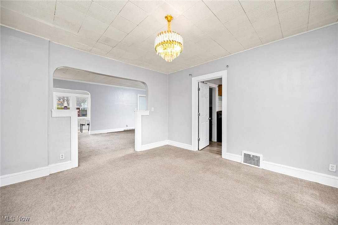 3368 Berea Road Cleveland, OH 44111 - Photo 6 of 26 Spare room featuring light colored carpet, a chandelier, and arched walkways