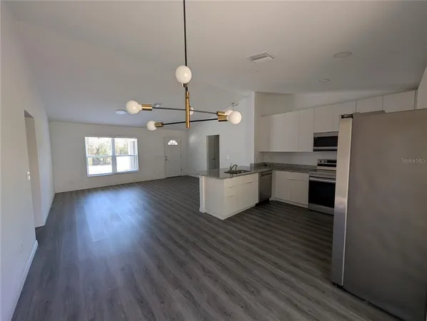 a view of kitchen with granite countertop stainless steel appliances cabinets a sink and a wooden floor
