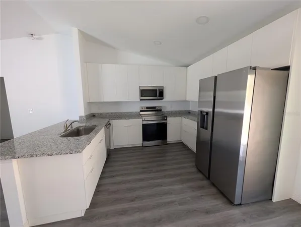 a kitchen with stainless steel appliances granite countertop a refrigerator a stove a sink and a microwave