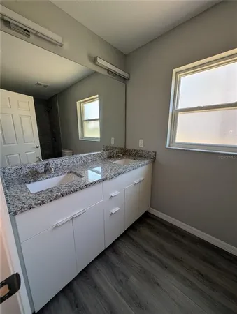 a bathroom with a granite countertop sink and a window