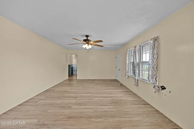 a view of an empty room with window and wooden floor