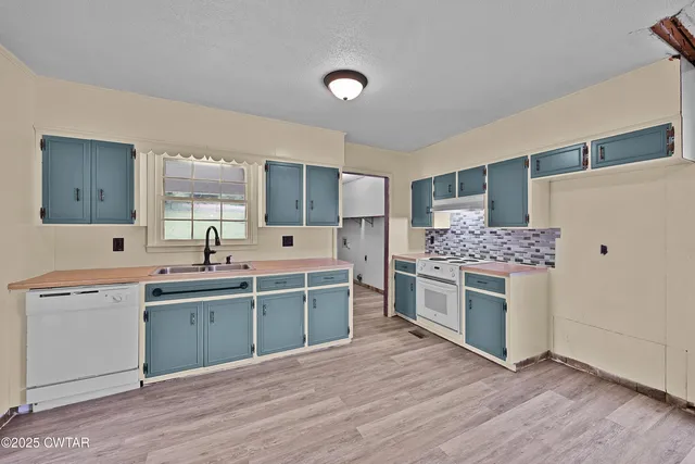 a view of an empty room with wooden floor and a bathroom