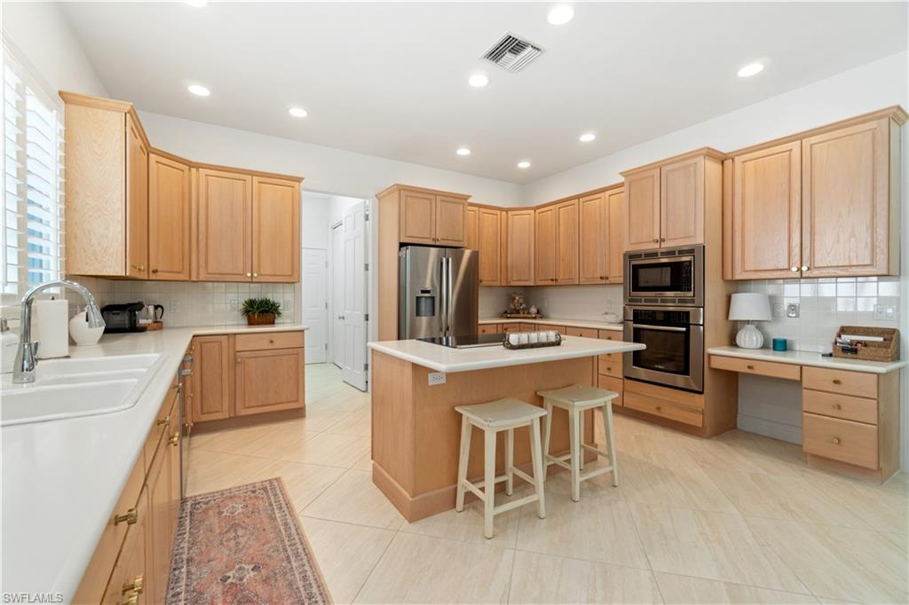 764 Ashburton Drive Naples, FL 34110 - Photo 12 of 30 a large kitchen with kitchen island granite countertop a stove top oven a sink a counter space and cabinets