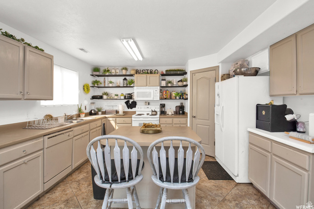 339 North Farm Mdw Road Farmington, UT 84025 - Photo 12 of 17 Kitchen featuring an island with seating, a white microwave, and built-in open shelving