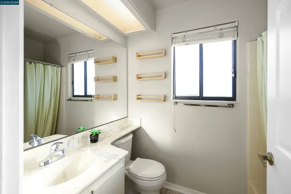 a bathroom with a granite countertop sink toilet a mirror and shower