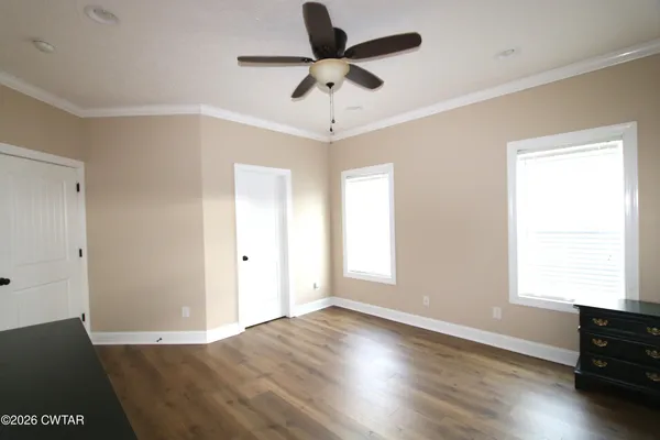 a view of empty room with wooden floor and fan