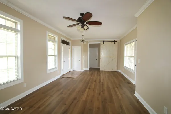 a view of empty room with wooden floor and fan