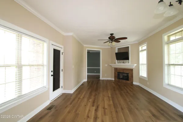 a view of a livingroom with a fireplace a ceiling fan and wooden floor