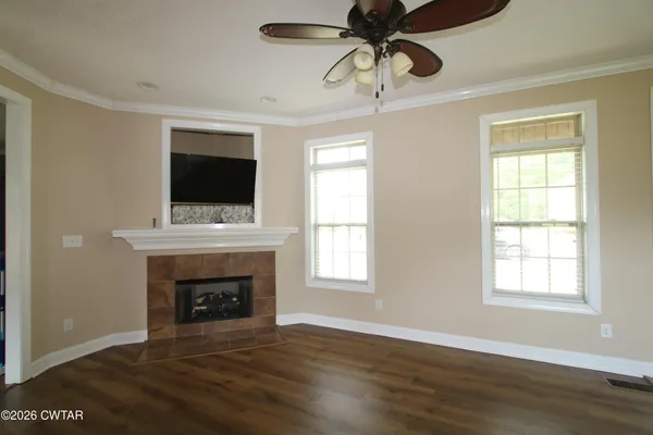a view of an empty room with wooden floor fireplace and a window