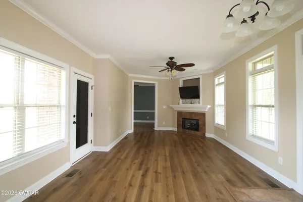 a view of a livingroom with a fireplace wooden floor and windows