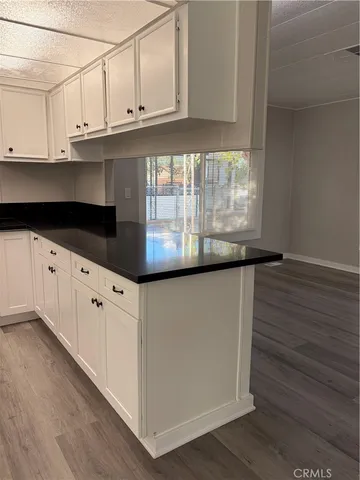 a kitchen with granite countertop white cabinets and a wooden floor