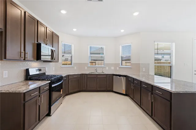 a kitchen with stainless steel appliances granite countertop a stove sink microwave and window