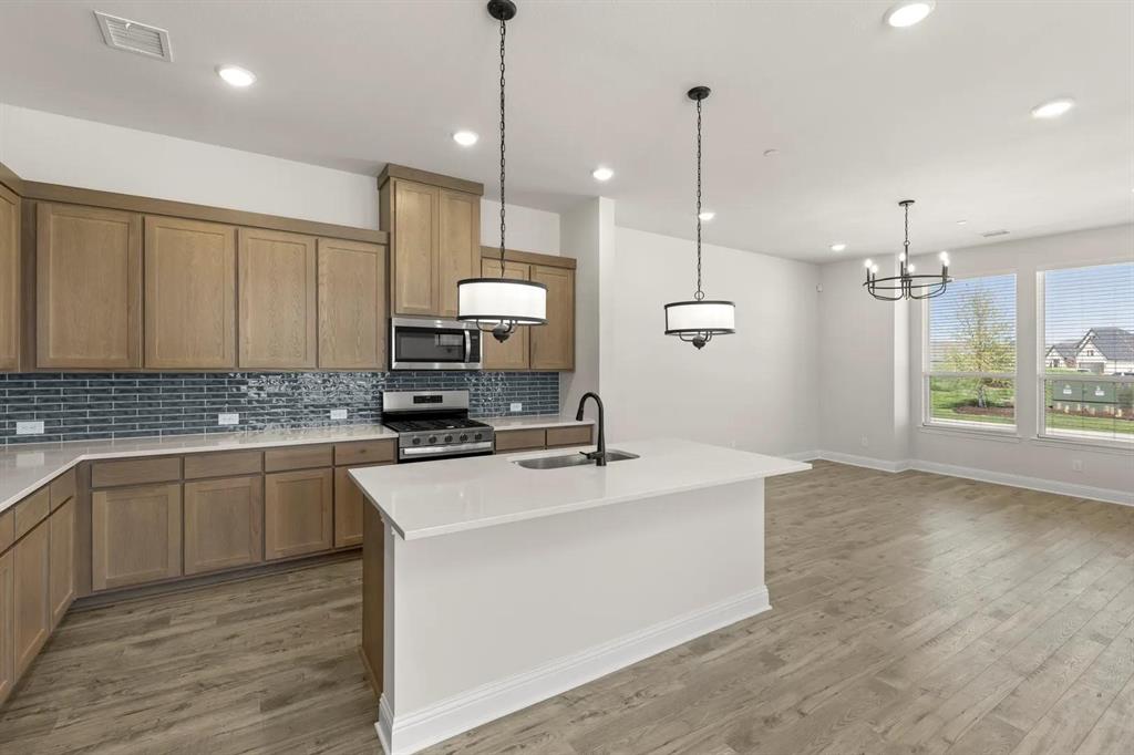 3900 Keya Drive Prosper, TX 75078 - Photo 4 of 36 a kitchen with stainless steel appliances granite countertop a sink a stove and a wooden floor