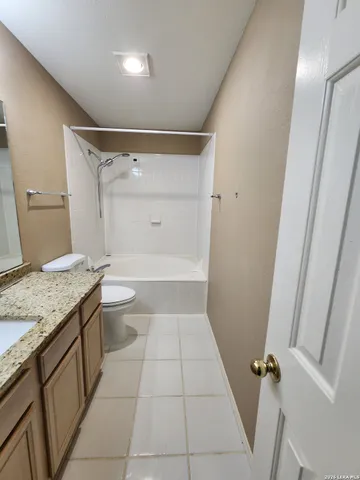 a bathroom with a granite countertop sink a toilet and shower