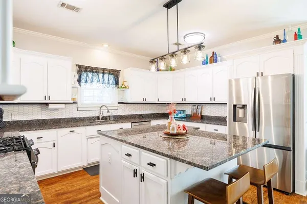 a kitchen with stainless steel appliances granite countertop a stove a sink and a microwave