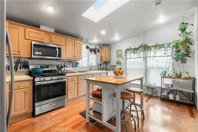 a kitchen with stainless steel appliances granite countertop a stove top oven a sink dishwasher and a refrigerator with wooden floor