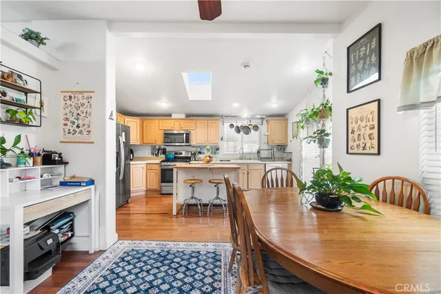a dining room with stainless steel appliances furniture a rug and a kitchen view