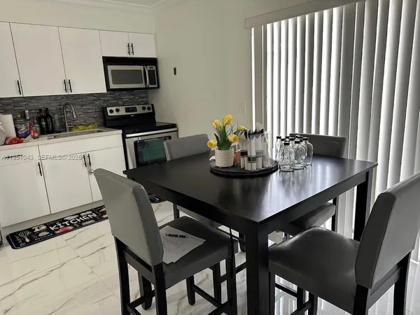 a kitchen with a dining table chairs and a refrigerator