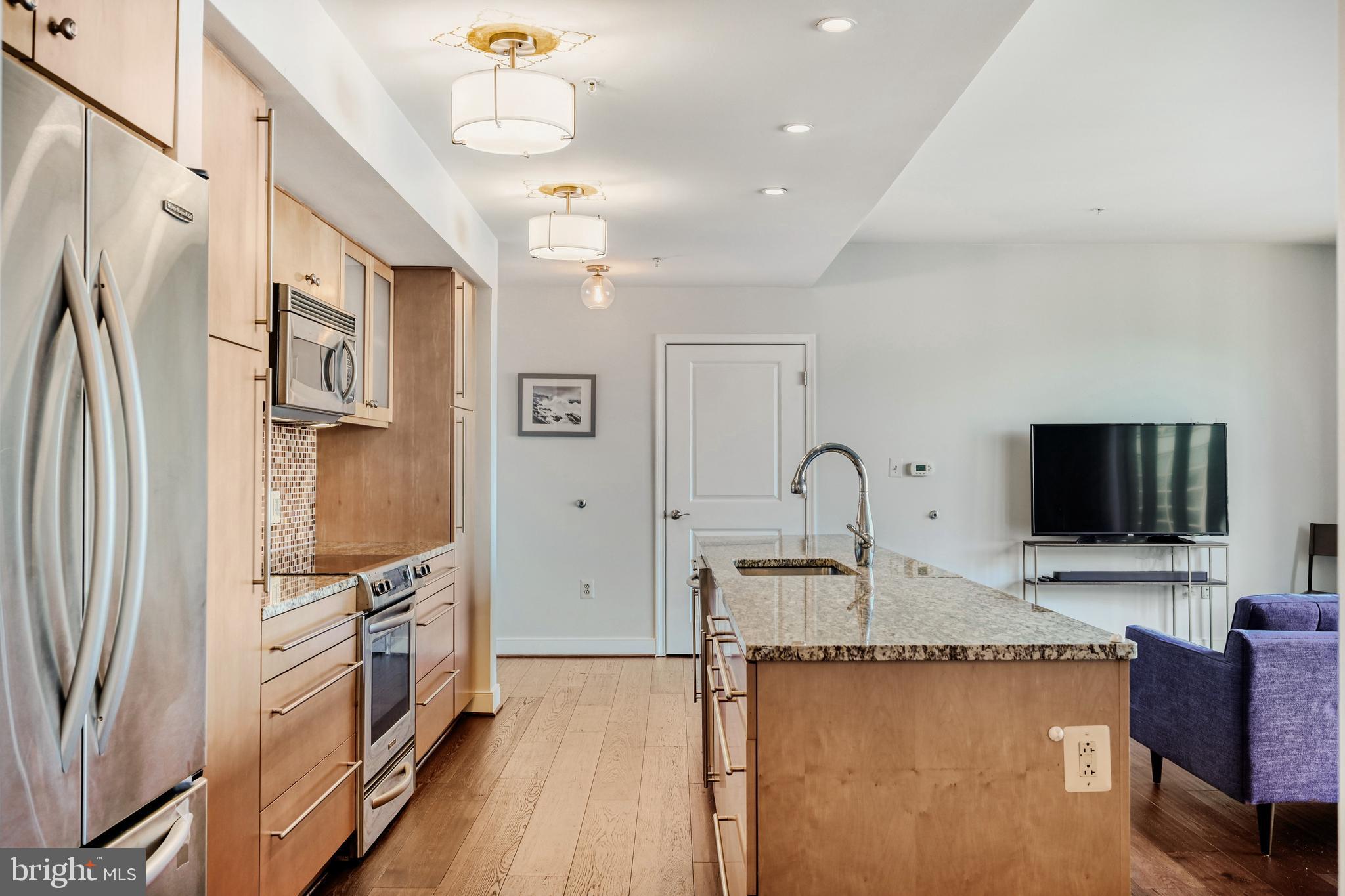 675 President Street, Unit 1406 Baltimore, MD 21202 - Photo 7 of 46 a kitchen with stainless steel appliances granite countertop a refrigerator a stove and a sink with wooden floor
