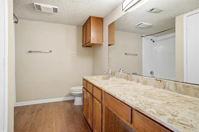 a bathroom with a granite countertop sink a toilet and a mirror
