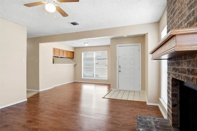 an empty room with wooden floor fireplace and windows