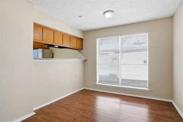 an empty room with wooden floor cabinet and windows