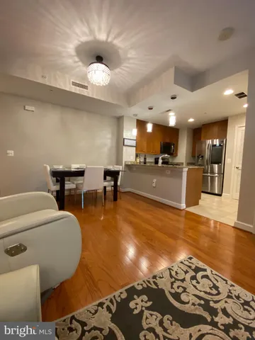 a kitchen with stainless steel appliances granite countertop a refrigerator a sink a stove a dining table and chairs with wooden floor