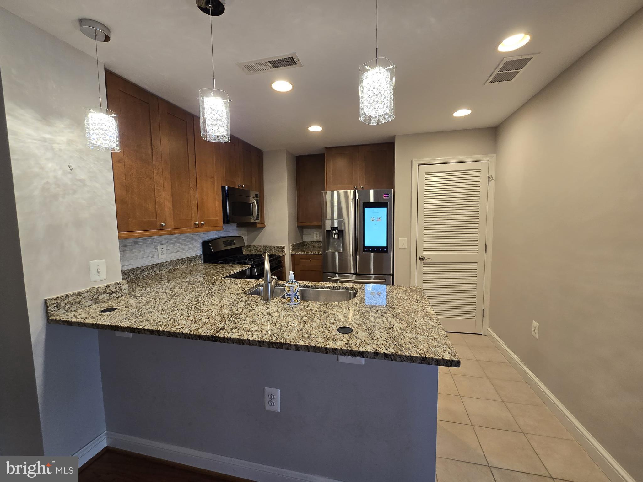 11990 Market Street, Unit 208 Reston, VA 20190 - Photo 5 of 16 a bathroom with a granite countertop sink a large mirror and shower