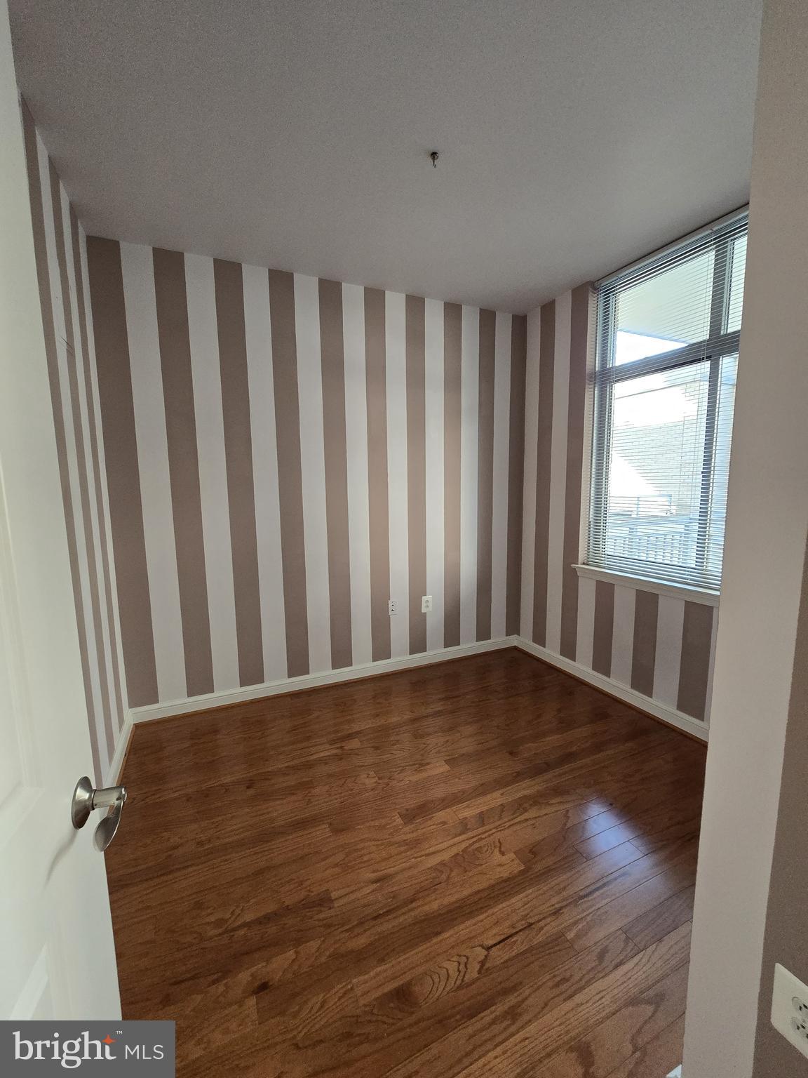 11990 Market Street, Unit 208 Reston, VA 20190 - Photo 9 of 16 a view of an empty room with wooden floor and a window