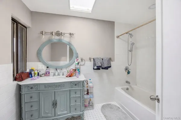 a bathroom with a sink vanity mirror bathtub shower and a mirror