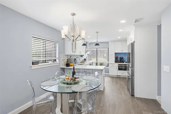 a view of a dining room and livingroom with furniture wooden floor kitchen chandelier