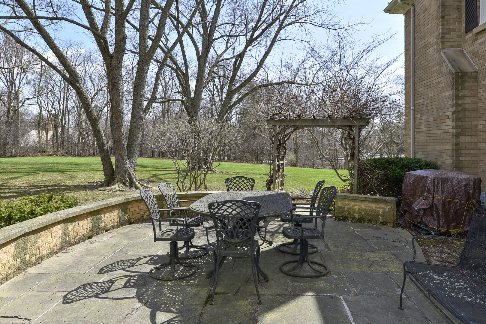 1495 Dunbar Road Inverness, IL 60067 - Photo 5 of 6 a view of a patio with table and chairs under an umbrella with large trees