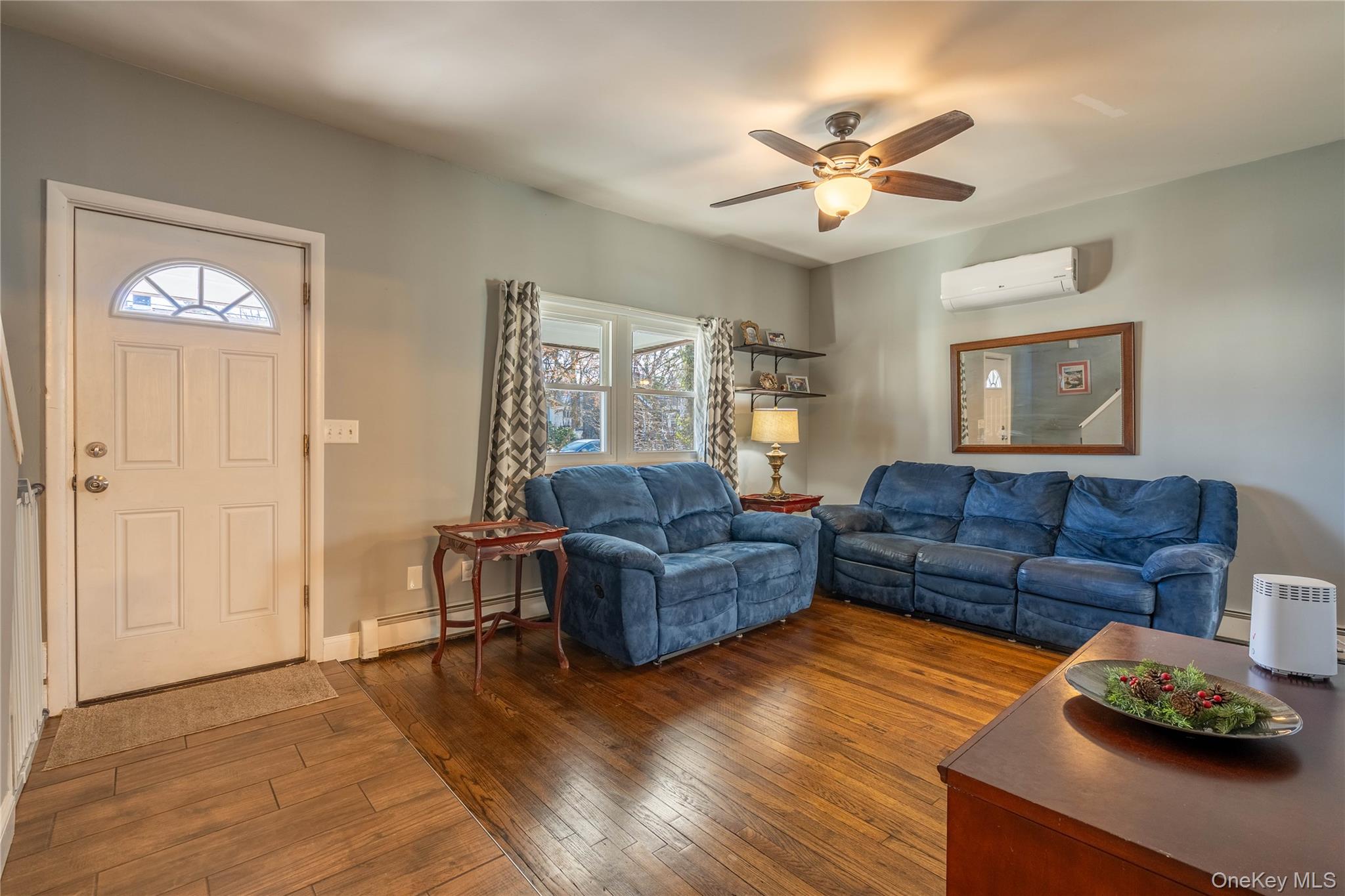 28 Maple Street Cornwall, NY 12518 - Photo 3 of 32 Living room featuring dark wood finished floors, a baseboard heating unit, an AC wall unit, and a ceiling fan