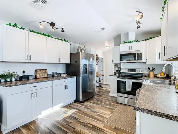 a kitchen with granite countertop a sink stainless steel appliances and white cabinets