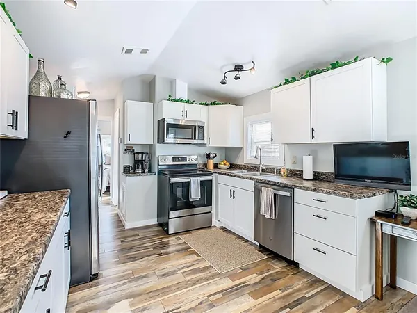 a kitchen with granite countertop a refrigerator stove and microwave