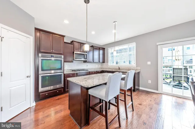 a kitchen with stainless steel appliances granite countertop a table chairs and a refrigerator