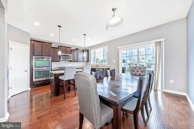 a open dining room with stainless steel appliances kitchen island granite countertop a table chairs and a refrigerator