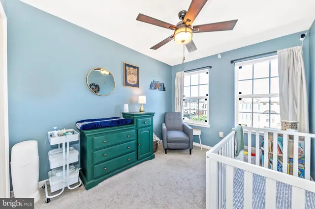 a bedroom with a baby crib a chandelier fan and a window