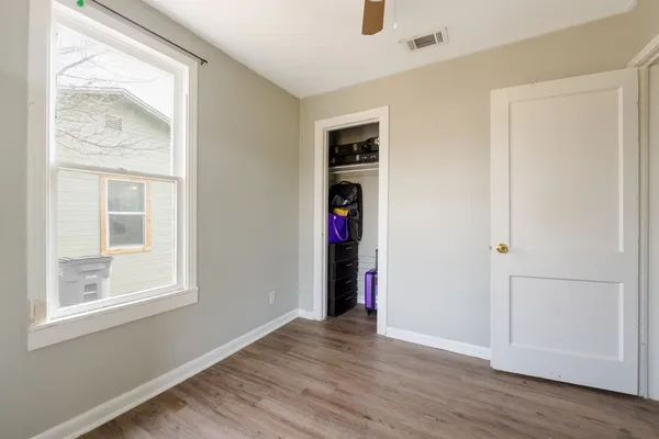 a view of an empty room with wooden floor and a window