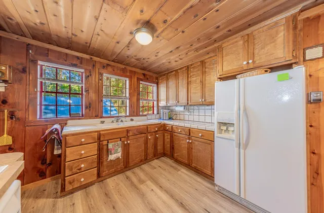 a kitchen with stainless steel appliances granite countertop a refrigerator a sink dishwasher a stove and white countertops with wooden floor