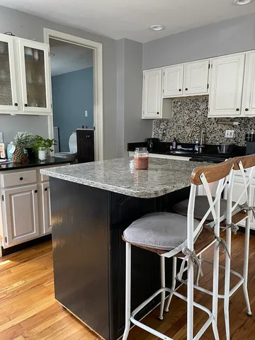 a kitchen with kitchen island granite countertop a table chairs sink and cabinets
