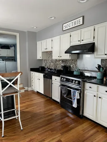 a kitchen with stainless steel appliances a stove a sink cabinets and wooden floor