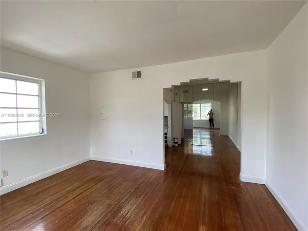 a view of an empty room with wooden floor and a window