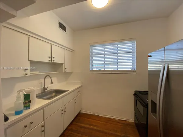 a kitchen with a refrigerator a sink and wooden floor