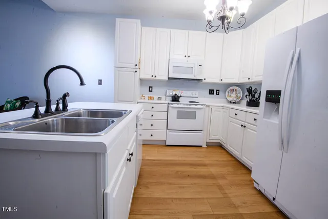 a large white kitchen with cabinets a sink a stove and refrigerator