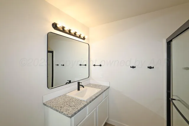 a bathroom with a granite countertop sink and a mirror